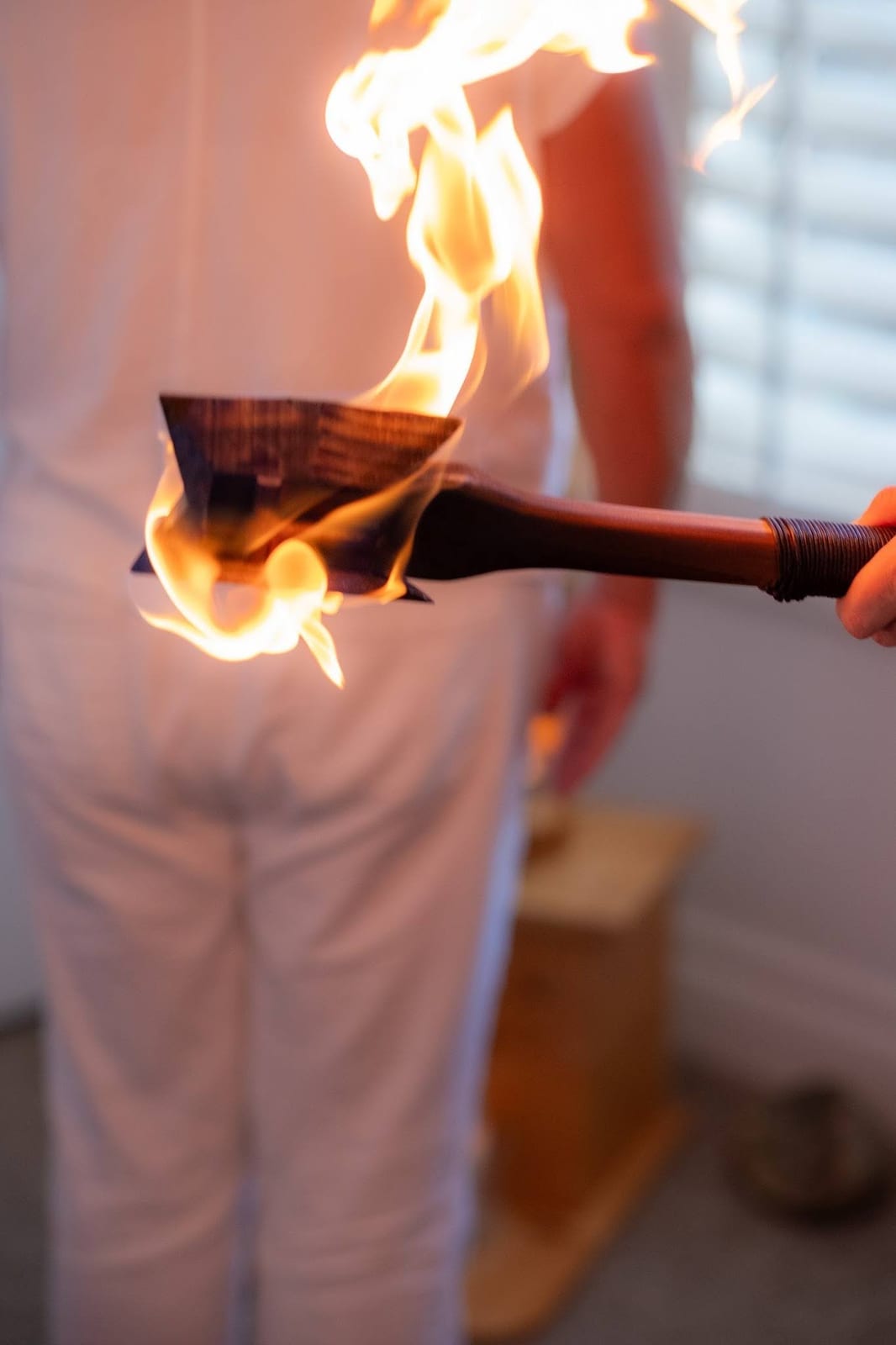 A ceremonial wooden healing tool held within a bright flame