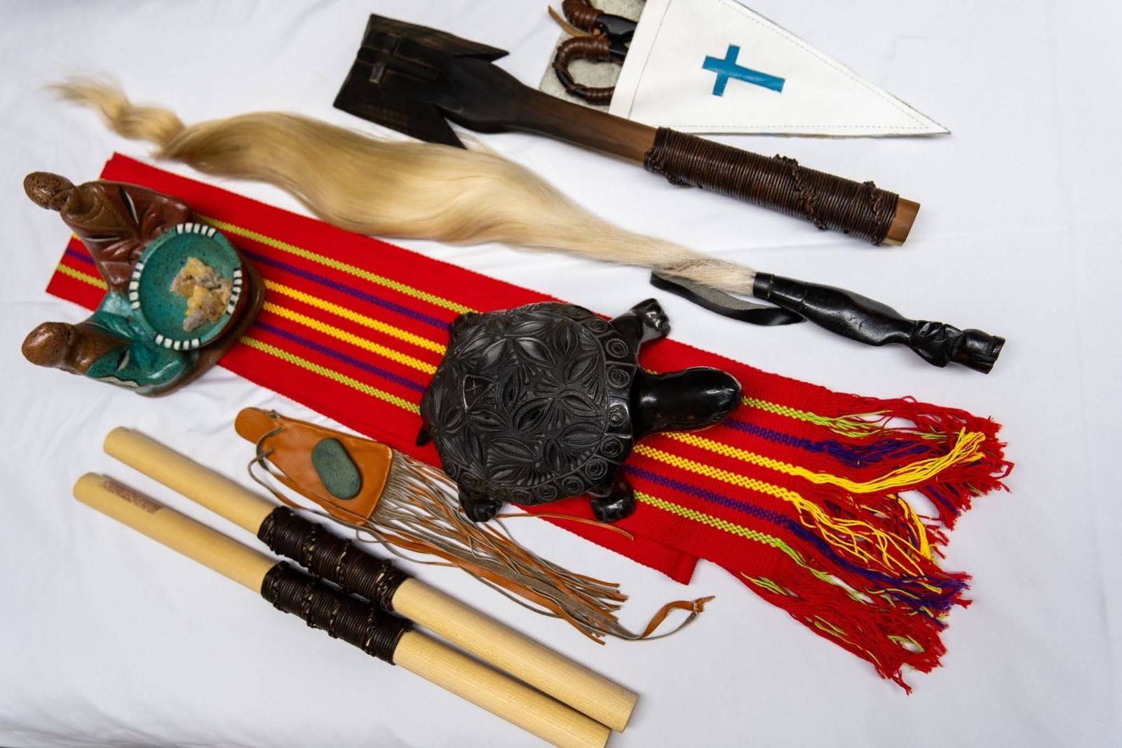 Traditional shamanic healing tools arranged over a vivid red woven textile